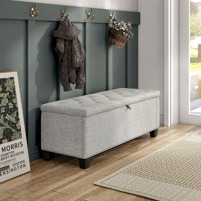 Right facing modern off white upholstered storage bench with a lift top in a room with accessories
