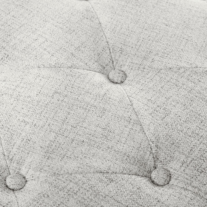 Close up of the button tufting of a modern off white upholstered storage bench with a lift top on a white background