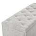Right facing close up of the tufted top of a modern off white upholstered storage bench with a lift top on a white background