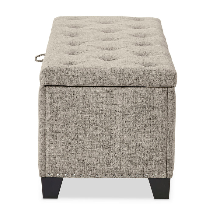 Front facing side view of a modern light brown upholstered storage bench with a lift top on a white background