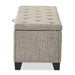 Front facing side view of a modern light brown upholstered storage bench with a lift top on a white background