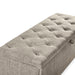 Right facing close up of the tufted top of a modern light brown upholstered storage bench with a lift top on a white background