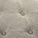 Close up of the button tufting of a modern light brown upholstered storage bench with a lift top on a white background