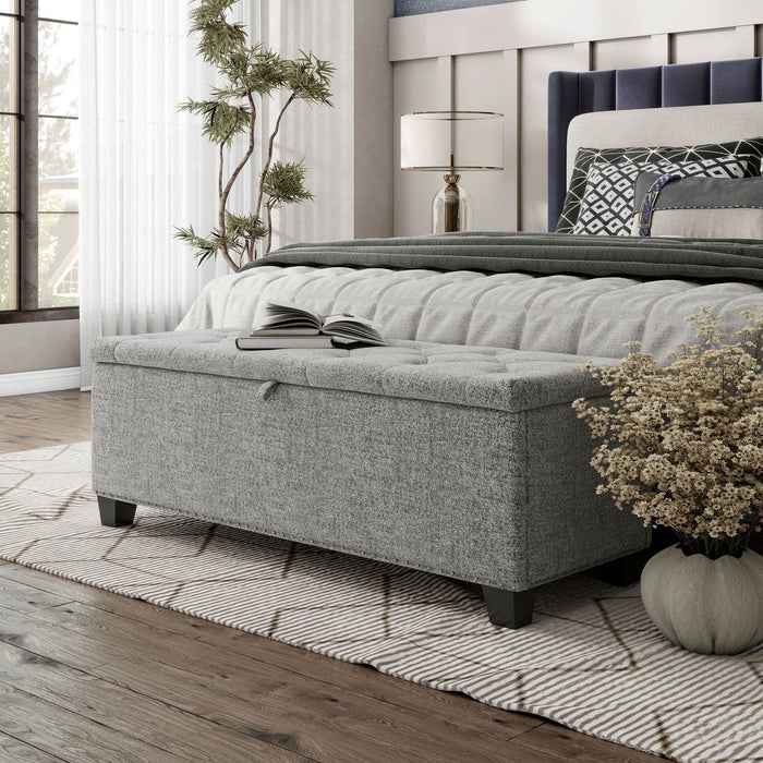 Left facing modern light grey upholstered storage bench with a lift top in a room with accessories
