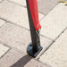 Close up view of the support leg of a modern red portable camping gazebo canopy with roof and anchors on patio paver stones