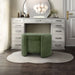 Left facing modern tufted green chenille round storage ottoman with a flip top in a room with accessories