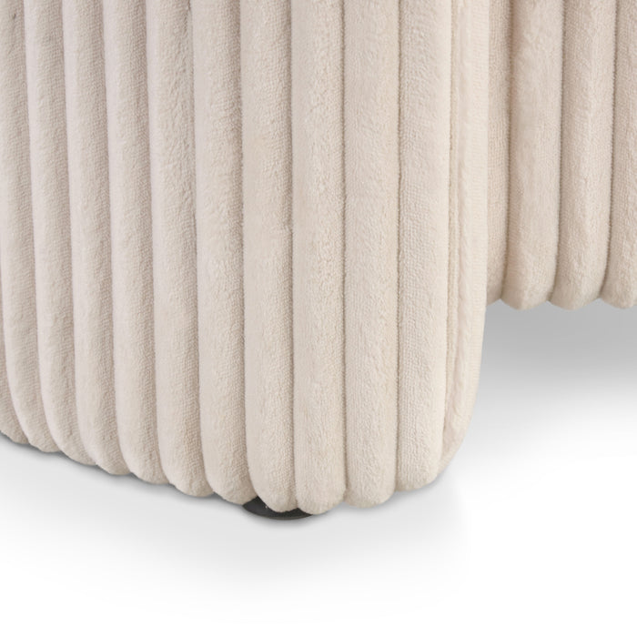 Left facing close up of a modern tufted beige pink chenille round storage ottoman with a flip top on a white background