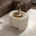 Left facing bird's eye view of a modern tufted beige pink chenille round storage ottoman with a flip top in a room with accessories