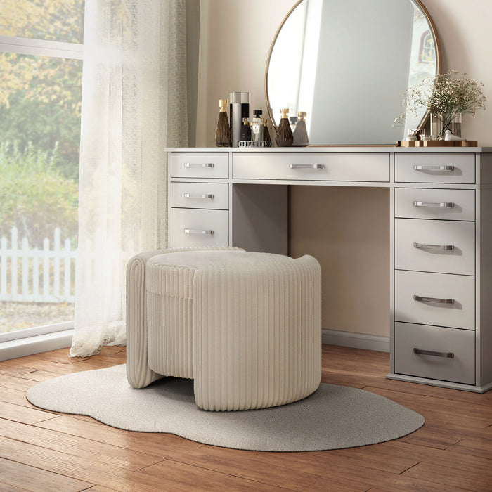 Left facing modern tufted beige pink chenille round storage ottoman with a flip top in a room with accessories