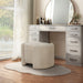 Left facing modern tufted beige pink chenille round storage ottoman with a flip top in a room with accessories