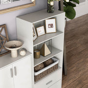 Right facing high camera view of a durable modern three-shelf white storage bookcase in a larger modular configuration in a room with accessories