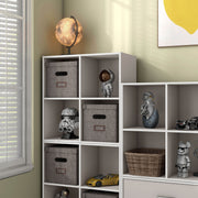 Left facing durable modern four-cubby taupe grey storage bookcase as part of a larger modular configuration in a room with accessories