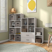 Left facing durable modern four-cubby taupe grey storage bookcase as part of a larger modular configuration in a room with accessories