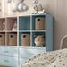 Left facing durable modern four-cubby light blue storage bookcase as part of a larger modular configuration in a room with accessories
