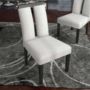 Right facing single view of a set of two contemporary black with white boucle dining side chairs in a room with accessories