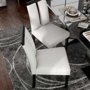 Right facing bird's eye single view of a set of two contemporary black with white boucle dining side chairs in a room with accessories