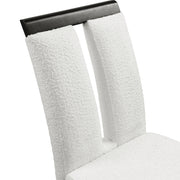 Right facing close up single view of a set of two contemporary black with white boucle dining side chairs on a white background