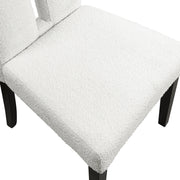 Right facing close up single view of a set of two contemporary black with white boucle dining side chairs on a white background