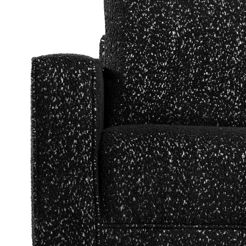 Front facing close up of the armrest and upholstery of a contemporary black and metallic boucle accent armchair on a white background