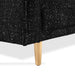 Right facing close up of the leg and upholstery of a contemporary black and metallic boucle accent armchair on a white background