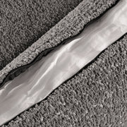 Right facing close up of the zippered pillow cover of a contemporary charcoal gray and metallic boucle accent armchair on a white background