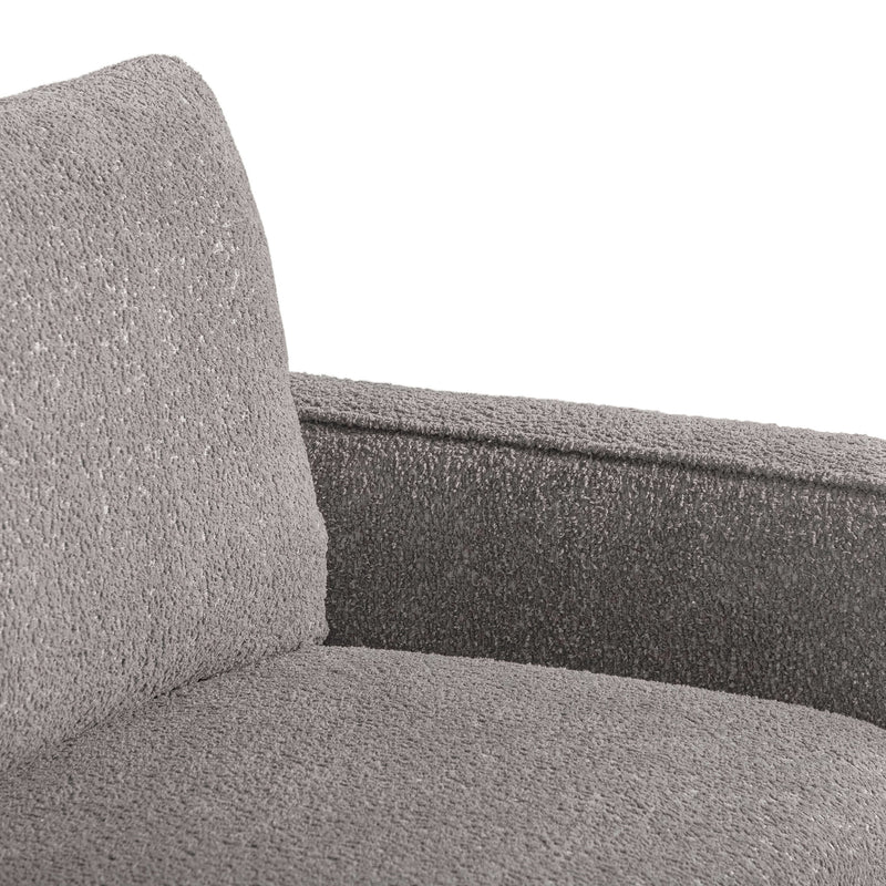 Right facing close up of the inner armrest of a contemporary charcoal gray and metallic boucle accent armchair on a white background