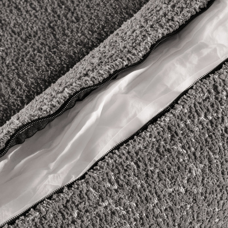 Right facing close up of the zippered pillow cover of a contemporary charcoal gray and metallic boucle sofa on a white background