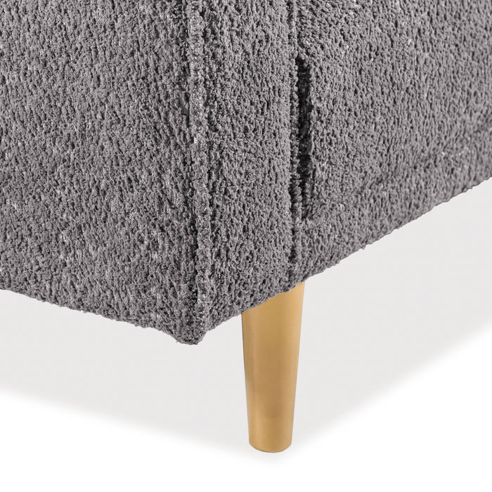 Right facing close up of the leg and upholstery of a contemporary charcoal gray and metallic boucle sofa on a white background