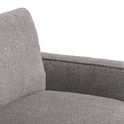 Right facing close up of the inner armrest of a contemporary charcoal gray and metallic boucle sofa on a white background