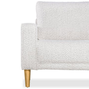 Front facing close up of the armrest, leg, and upholstery of a contemporary off-white metallic boucle accent armchair on a white background