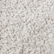 Swatch of the upholstery fabric on a contemporary off-white metallic boucle loveseat