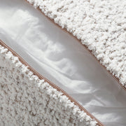 Close up of the zippered pillow cover of a contemporary off-white metallic boucle loveseat on a white background