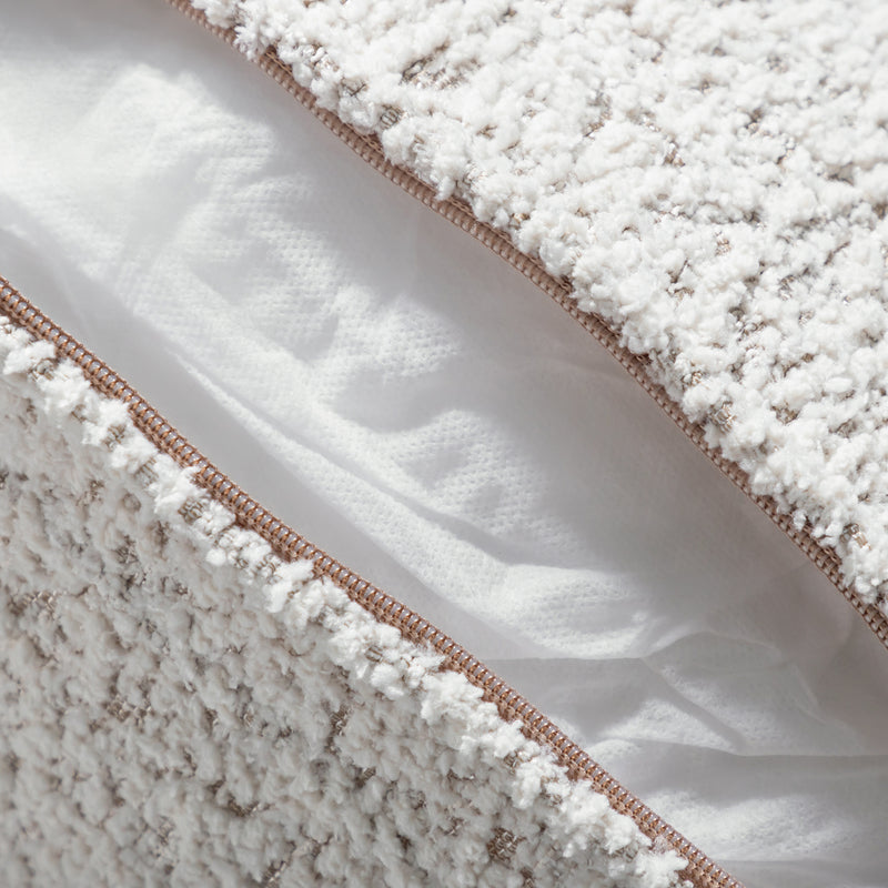 Close up of the zippered pillow cover of a contemporary off-white metallic boucle sofa on a white background