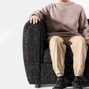 Front facing close up of a contemporary black metallic boucle shelter armchair with a person seated on a white background