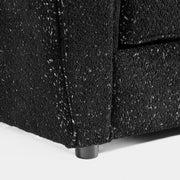 Right facing close up of the leg of a contemporary black metallic boucle shelter sofa on a white background
