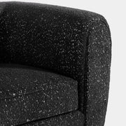 Right facing close up of the rounded armrest of a contemporary black metallic boucle shelter sofa