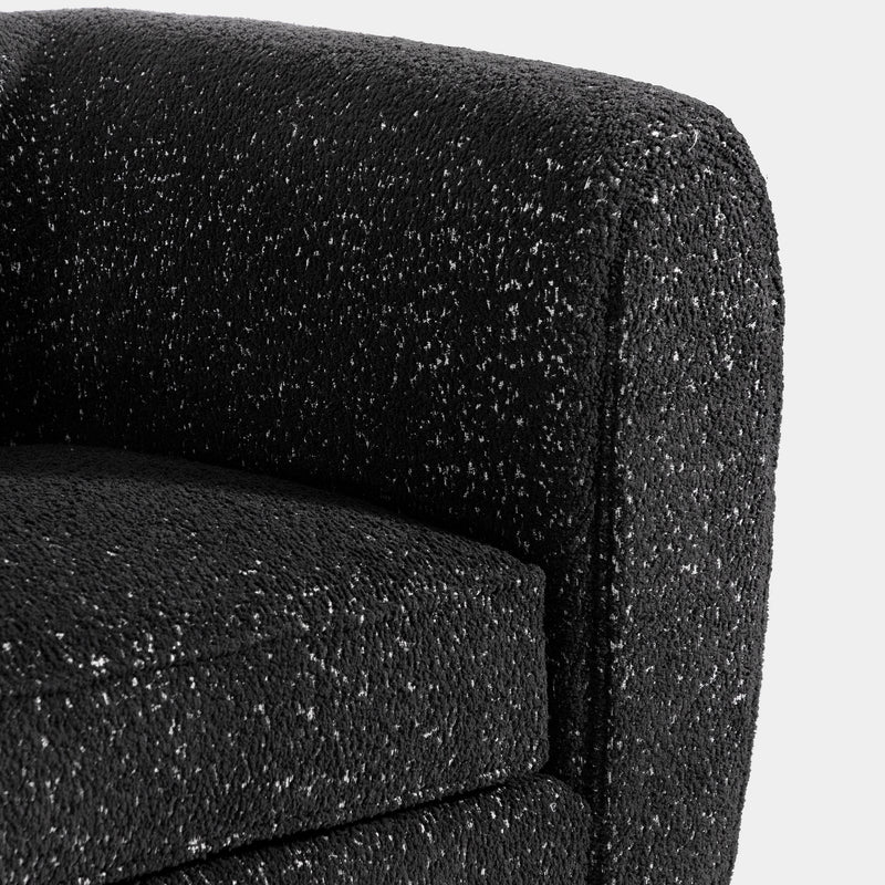 Right facing close up of the rounded armrest of a contemporary black metallic boucle shelter sofa