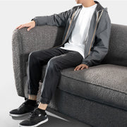 Left facing close up of a person seated on a contemporary charcoal gray metallic boucle shelter sofa on a white background