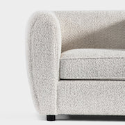 Front facing close up of the armrest and leg of a contemporary off-white metallic boucle shelter armchair on a white background