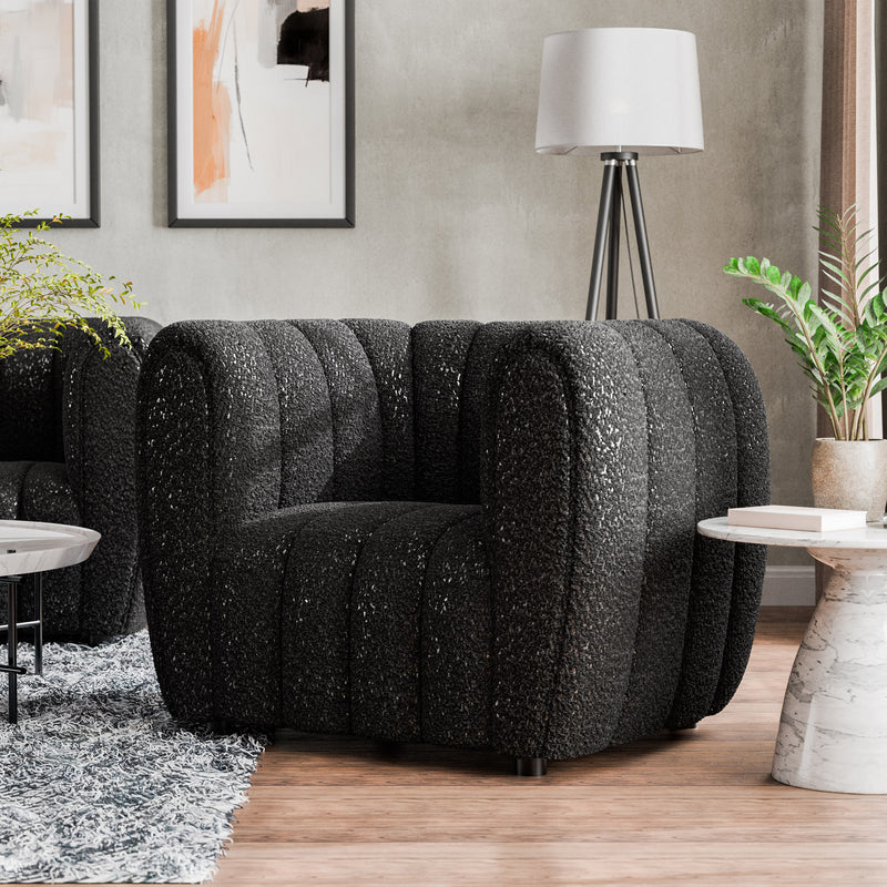 Left facing contemporary black and metallic boucle tufted shelter armchair in a living room with accessories
