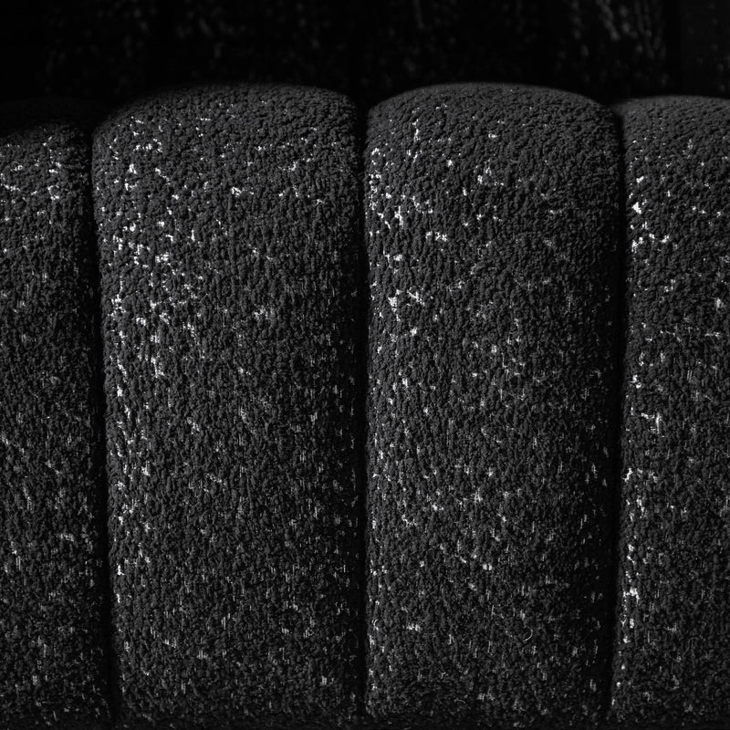 Front facing close up upholstery and tufting of a contemporary black and metallic boucle tufted shelter armchair on a white background