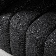 Left facing close up upholstery and tufting of a contemporary black and metallic boucle tufted shelter armchair on a white background