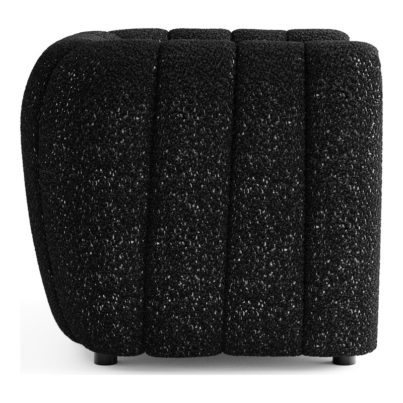 Front facing side view of a contemporary black and metallic boucle tufted shelter armchair on a white background