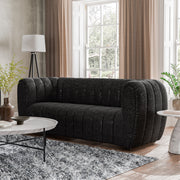 Left facing contemporary black and metallic boucle tufted shelter sofa in a living room with accessories