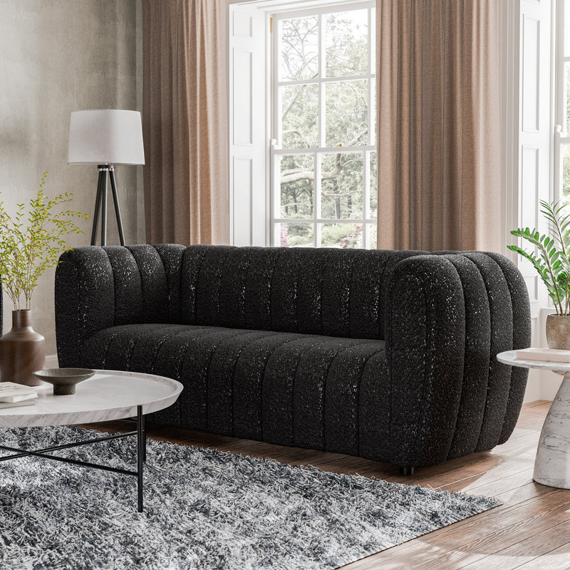 Left facing contemporary black and metallic boucle tufted shelter sofa in a living room with accessories