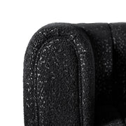Front facing close up upholstery and rounded armrest of a contemporary black and metallic boucle tufted shelter sofa on a white background