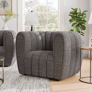 Right facing contemporary charcoal gray and metallic boucle tufted shelter armchair in a living room with accessories