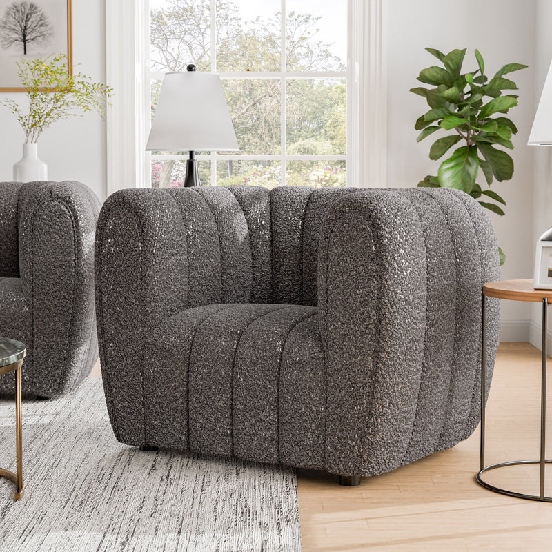 Right facing contemporary charcoal gray and metallic boucle tufted shelter armchair in a living room with accessories