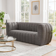 Left facing contemporary charcoal gray and metallic boucle tufted shelter sofa in a living room with accessories