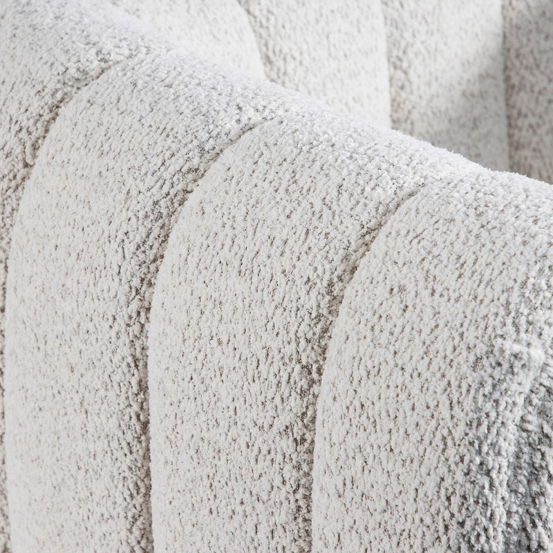 Right facing close up view of the upholstery and tufting on a contemporary off-white metallic boucle tufted shelter armchair on a white background